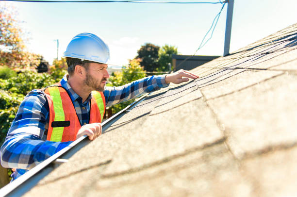 A man with hard hat standing on steps inspecting house roof